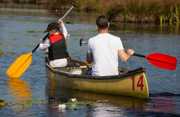 little girl rowing with dad on a yellow kayak
