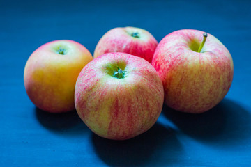 Several ripe pink-yellow apples on a blue background.