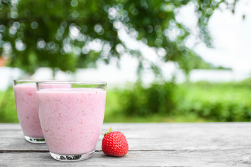 A glass of fresh cold smoothie with berries and cherrys on a wooden table, summer set, outdoor greed blured background,boke.