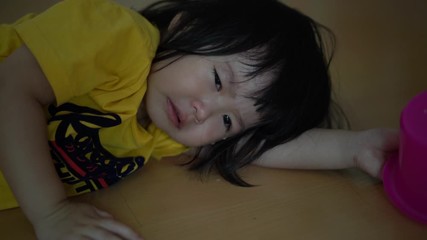 The little Asian girl very angry and upset, frowning her brow and showing a tongue. Bad mannered little girl  Crying in bed room