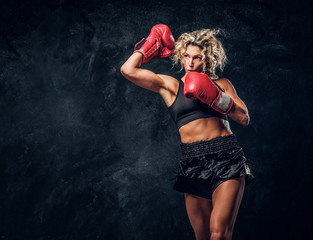 Fototapeta na wymiar Blonde experienced boxer is demonstrating her tactic attack wearing special gloves.