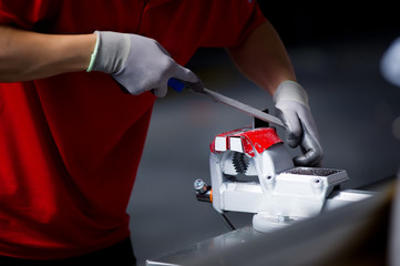 close-up of a worker in a red t-shirt processing a metal workpiece clamped in a vice