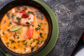 famous delicious Thai Tom yum spicy soup with shrimps and coconut milk on black table. close up