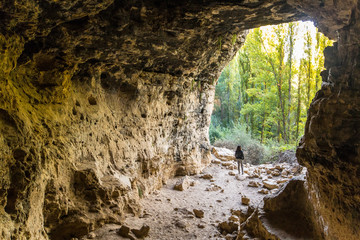 A cave of the Senda de la Vega in Segovia and a young girl at the entrance, Spain