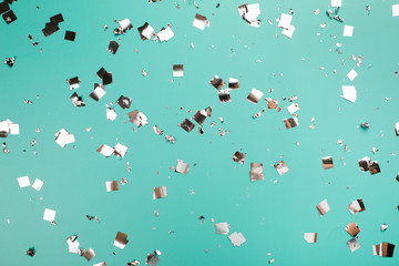 Falling silver confetti on mint backdrop. Holiday concept.