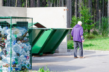 concern for the ecology of the planet. separate collection of garbage. plastic bottles. waste containers. separate place. elderly man, senior citizen, take out the trash. waste separation.