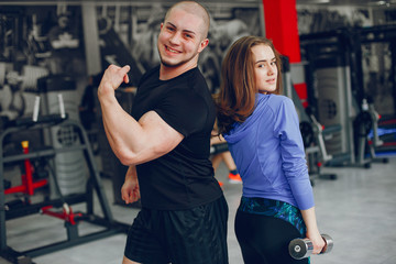 A young and beautiful girl with her boyfriend training in a gym