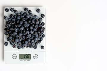 Electronic kitchen scale with blueberries, with copy space
