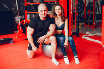 Fototapeta na wymiar A young and beautiful girl with her boyfriend training in a gym