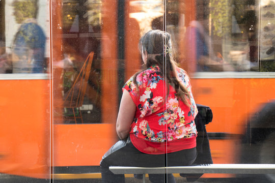 One woman sitting at a bus stop waiting