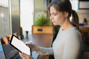 Female lifestyle fashion blogger using portable touch pad with empty copy space screen background for promotional content, sitting in coffee shop during recreation time in weekend. Online learning