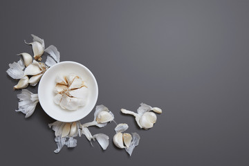 Garlic bulb, cloves and peel on gray background, flat lay with copy space