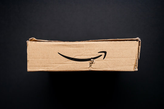 PARIS, FRANCE - APR 9, 2017: Directly above view of cardboard box from Amazon Prime with distinct online retailer logotype insignia and damaged pard