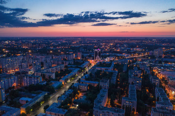 Fototapeta na wymiar Aerial view of night city with illuminated roads, car traffic and different buildings, drone shot