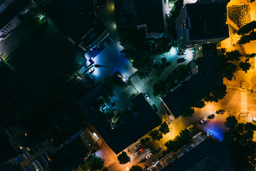 Aerial top down view of night city buildings and illuminated roads, drone photo