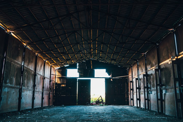 Large abandoned empty and dirty rusty iron hangar, creepy warehouse inside