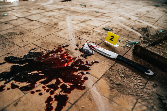 Crime scene with knife marked with number in blood of victim on floor. Investigation of cruel murder concept
