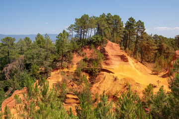 Ochre Trail in Roussillon, Hiking path in orange ocher cliffs surrounded by green forest in...