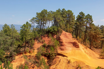 Ochre Trail in Roussillon, Hiking path in orange ocher cliffs surrounded by green forest in Provence, Southern France