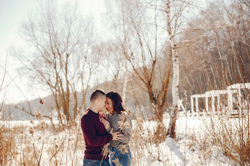 Cute couple have fun. Boy and girl in a winter park. Man in a red sweater. Brunette in a gray sweater