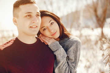 Cute couple have fun. Boy and girl in a winter park. Man in a red sweater. Brunette in a gray sweater