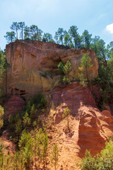 Ochre Trail in Roussillon, Hiking path in orange ocher cliffs surrounded by green forest in Provence, Southern France