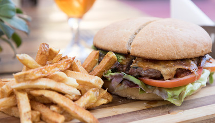 Delicious hamburger served with vegetables, french fries and a cold glass of beer