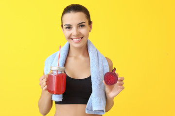 Young sporty woman with healthy beet juice on color background