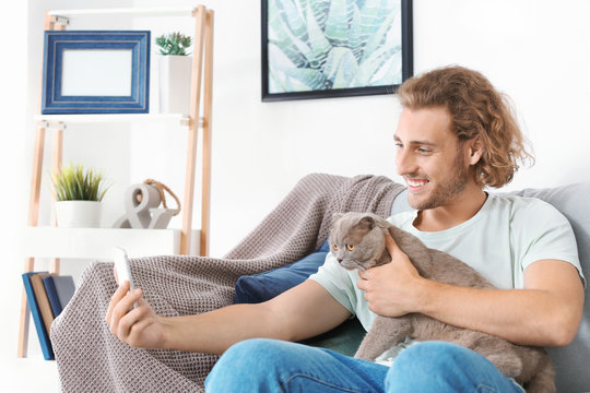 Man with cute funny cat taking selfie at home