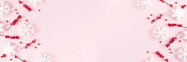 Christmas modern composition. Xmas decorations, red berries, snowflakes on pastel pink background. Christmas, New Year, winter concept. Flat lay, top view, copy space, banner