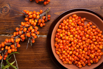 ripe sea buckthorn berries with branch on wooden table. close up. flat lay
