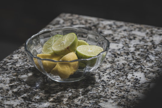 Picture of lemon and lime halves in a glass bowl. 