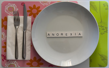 Empty plate with anorexia written inside in uppercase letters