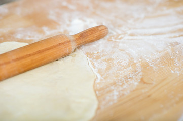 rolling pin and dough lie on a table sprinkled with flour