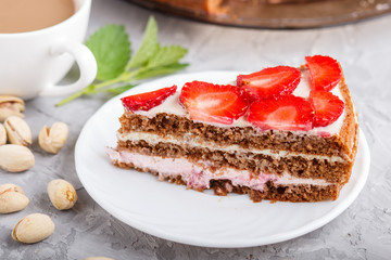 Homemade cake with yoghurt cream, strawberry and pistachio on a gray concrete  background. side view.