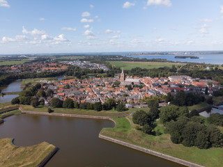 Fototapeta na wymiar Aerial view on the fortification city Naarden Vesting with its defensive constructions surrounding the village against a blue sky with clouds