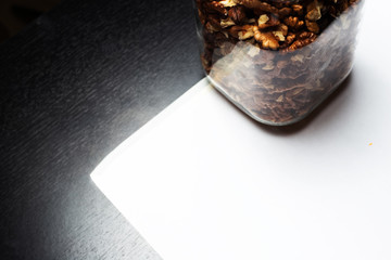 Close-up of glass jar with walnut, on black background.