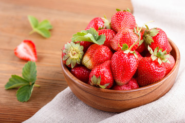 Fresh red strawberry in wooden bowl on wooden background. side view.