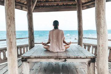 young woman meditating in a yoga pose at the beach