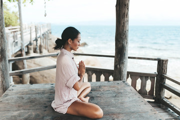 Young woman meditating in a yoga pose at the beach