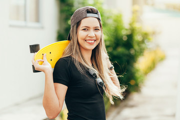 Portrait of smiling young female skateboarder with her skateboard outdoors