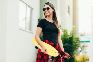 Portrait of smiling young female skateboarder with her skateboard outdoors