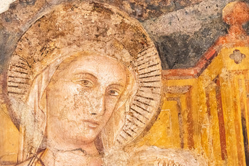Detail of medieval fresco showing the face of female catholic saint