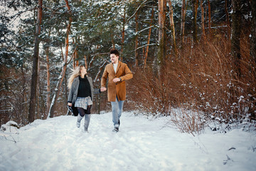 happy young couple walking through the park on a snowy day