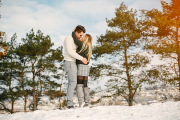 happy couple kissing and hugging in the park on a snowy winter day