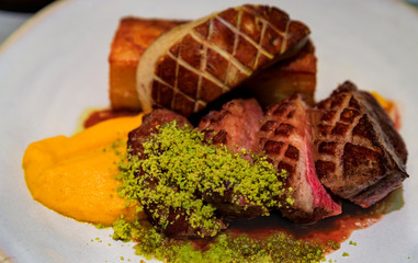 Plate of seared duck breast and foie gras with a side of potato gratin and sweet potato puree  at a restaurant in Porto