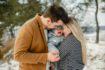 happy young family of three in the park on a snowy winter day