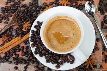Cup of coffee and coffee beans on wooden background from top view.
