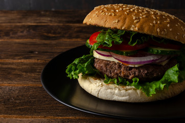 fresh tasty burger on black background on wooden table