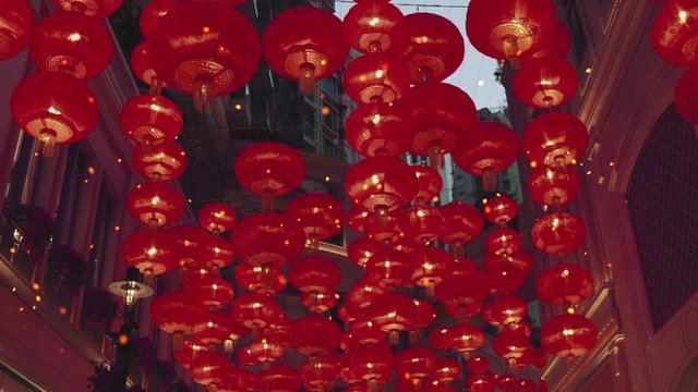 Red burning chinese lanterns rise into the air along a city street